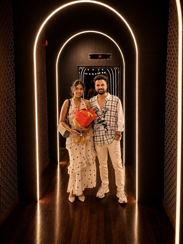 Heshan and Samadei under a lit archway, Samadei holding a bouquet.